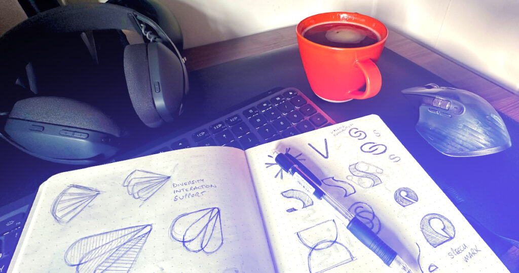 photograph of desk and keyboard with design sketch book and pencil