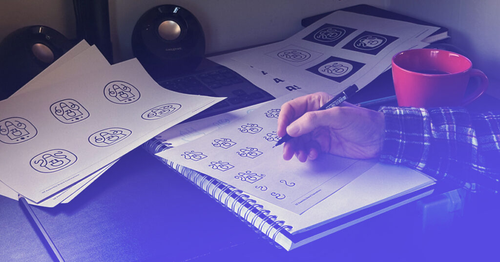 Photo of designer working on logo drafts at his desk.